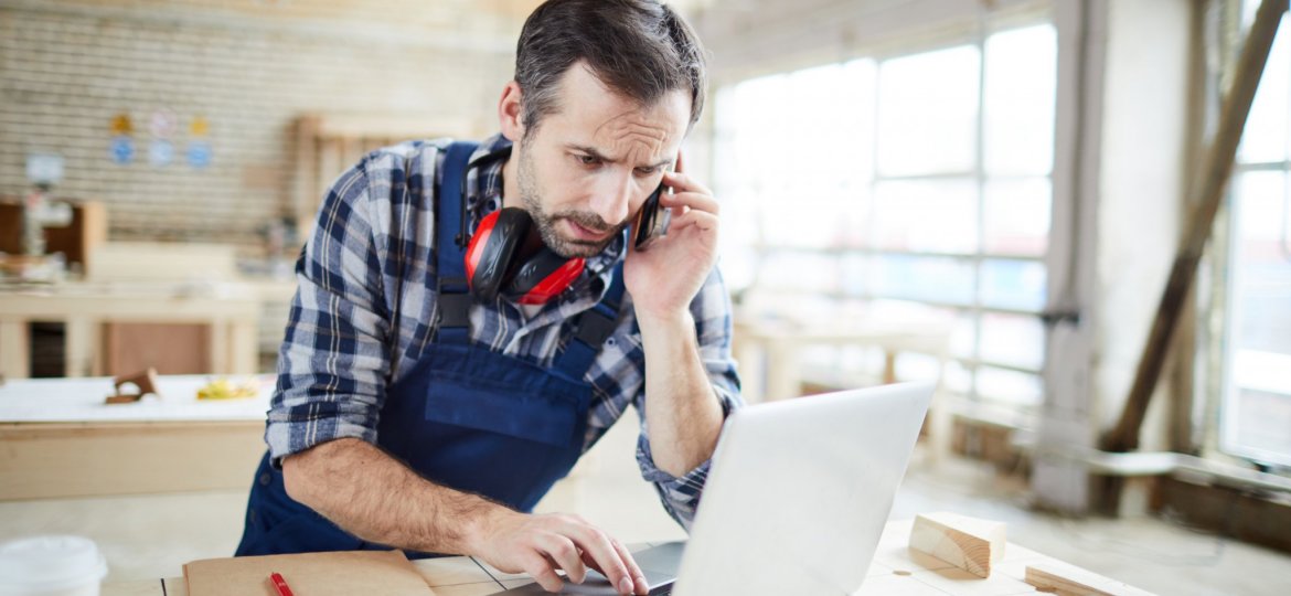 Confused carpenter checking information while talking by phone